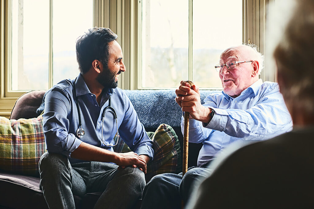 smiling doctor visiting senior man at home