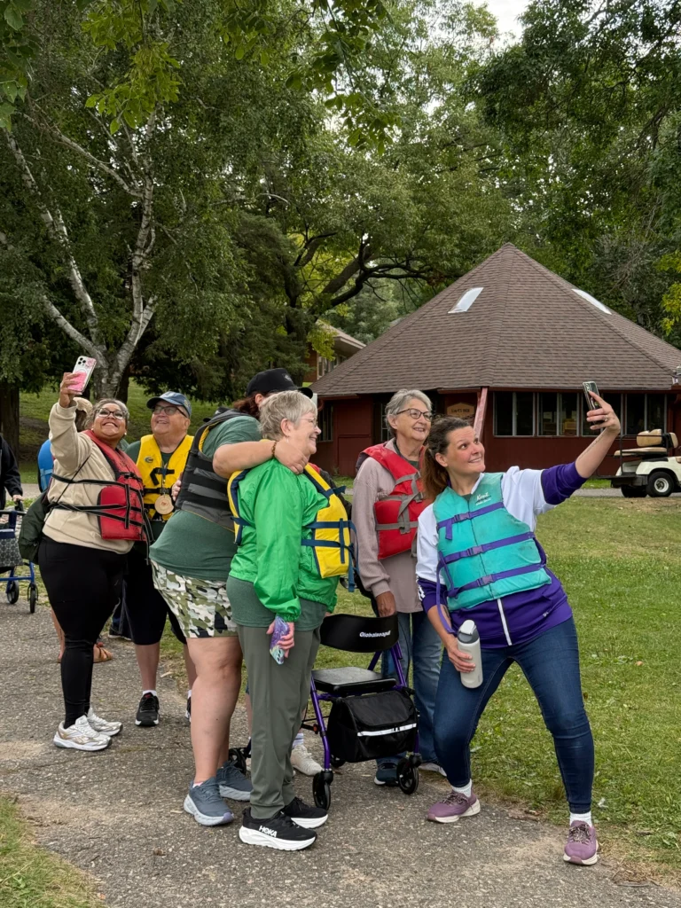 Campers wearing life jackets pause for a photo together before the accessible pontoon boat ride.