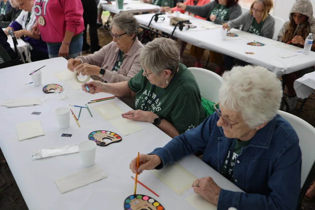 Three women, residents at Lifespark Senior Living communities, participate in a watercolor painting activity at Camp Joy, a summer camp for seniors.