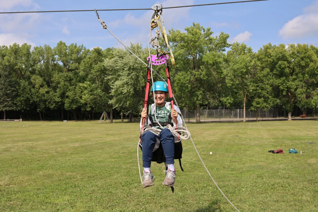 Camper prepares to land after riding the accessible zipline at Camp Joy.